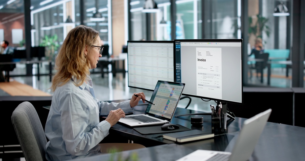 A billing specialist reviewing claims and an invoice on screen
